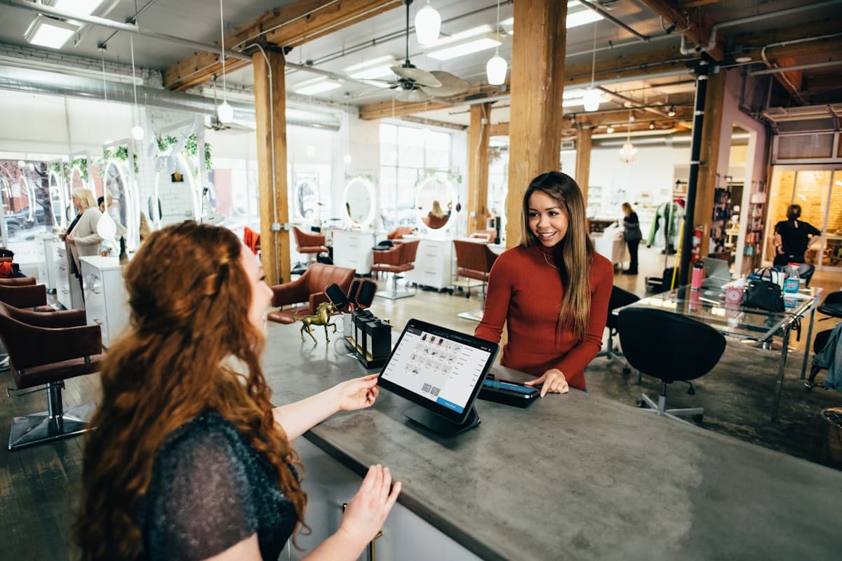 Customer service agents with headsets at adjacent workstations in a bright office